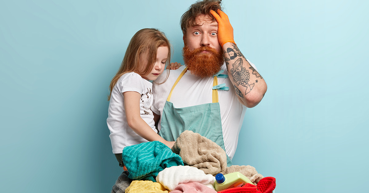 stressed out dad holding daughter and laundry basket